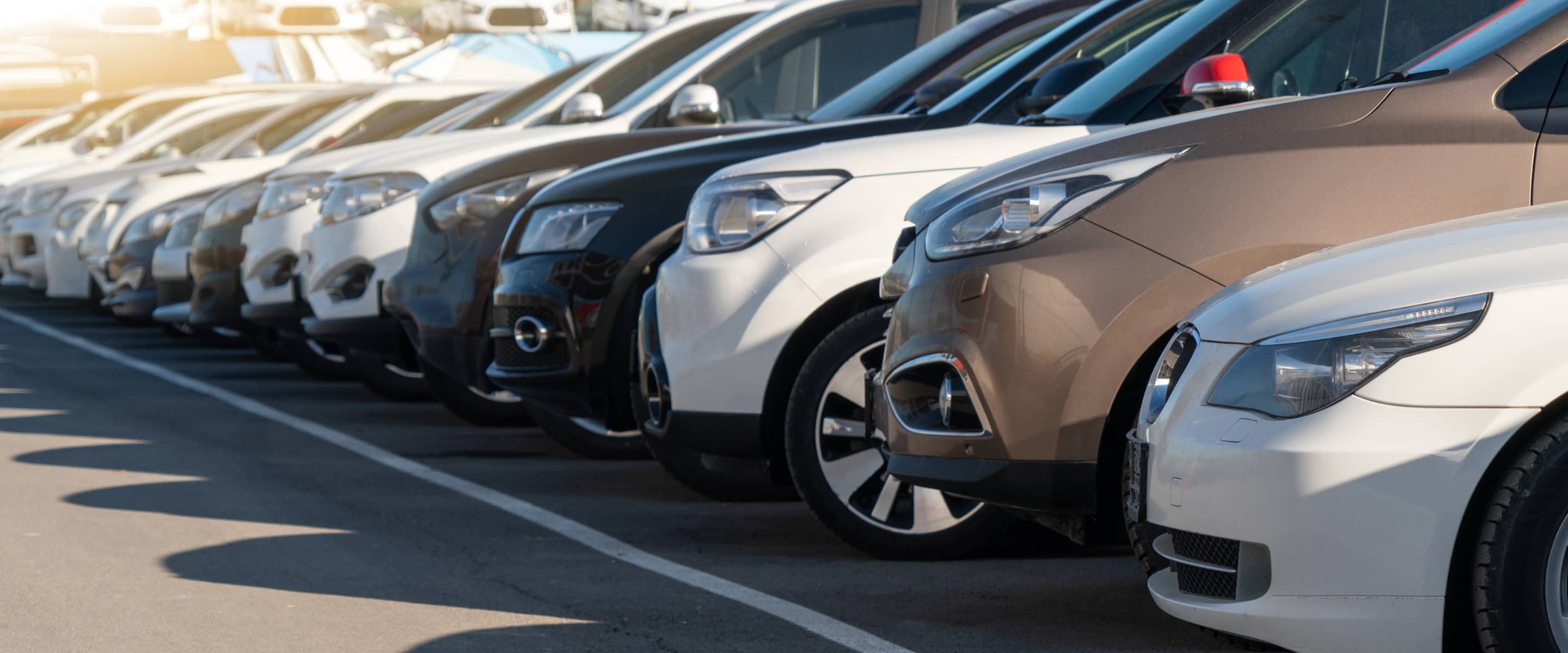 駐車場に整列しているさまざまな色の乗用車のフロントグリルとヘッドライト
