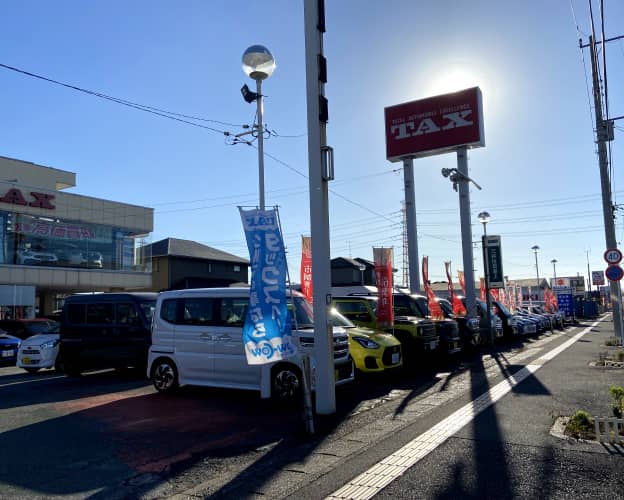 車両が並ぶ販売店の外観、TAXの看板が特徴的