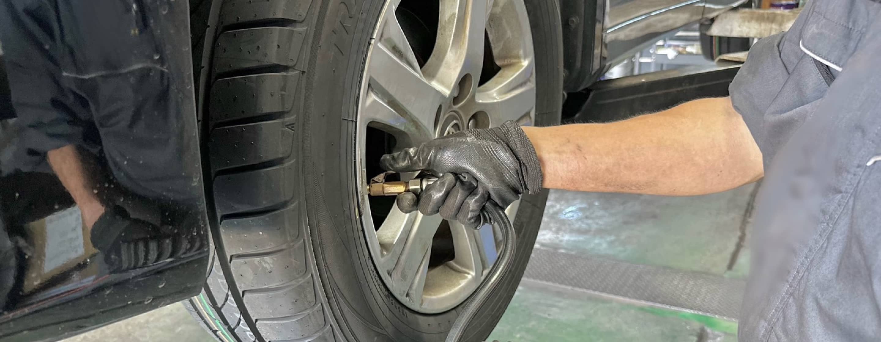 整備士が車のタイヤの空気圧を点検している様子